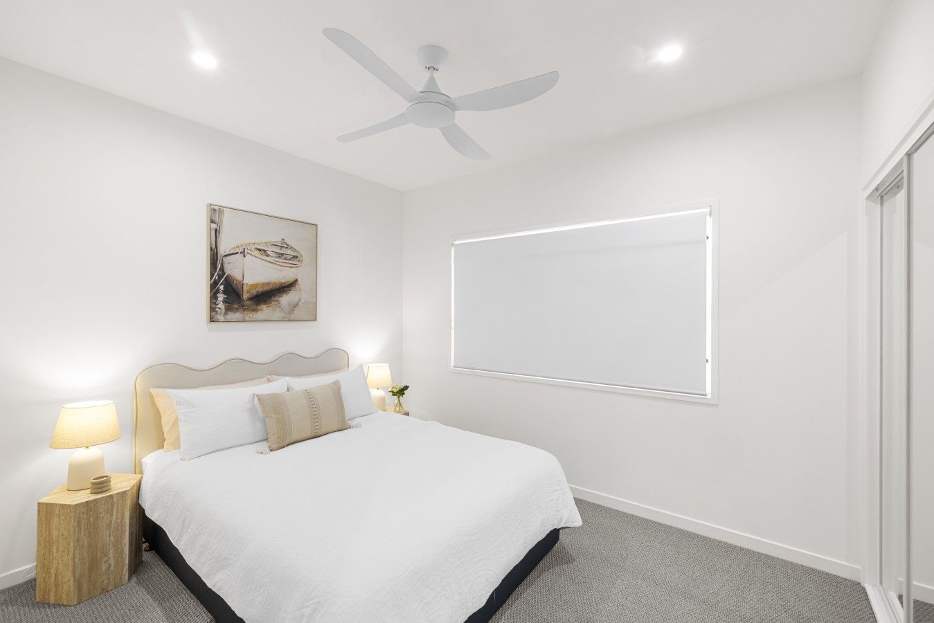 Une chambre à coucher avec un lit, des lampes de chevet, un ventilateur de plafond, un tableau et une fenêtre.