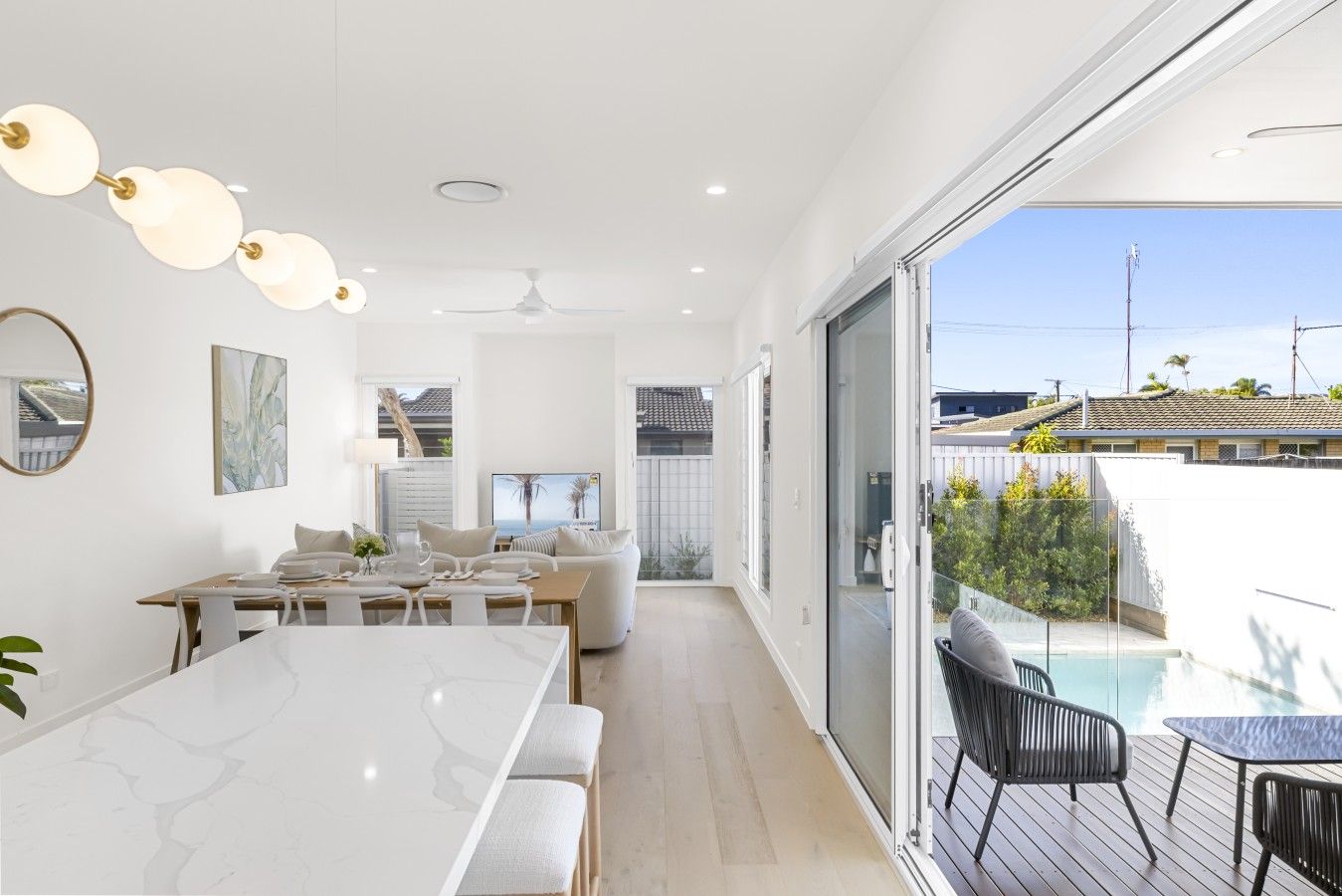 Et moderne interiør med spiseplads, opholdsstue og en balkon med pool.