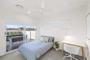 A light-filled bedroom with sliding door access to the balcony, study desk, and blue accent linen — practical, fresh, and full of natural light. - Your Buddina Escape:Swim, Sip & Unwind by the Pool (Buddina)