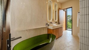 Une salle de bain moderne avec une baignoire verte, un meuble-lavabo avec un miroir et une vue sur l’extérieur.