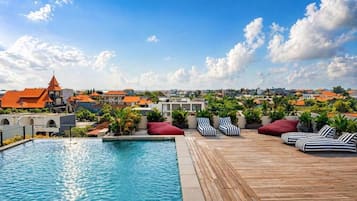 A rooftop pool area with lounge chairs and a view of the cityscape.