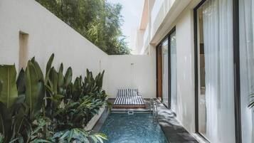 A swimming pool with a bench, surrounded by plants and a building with large windows.