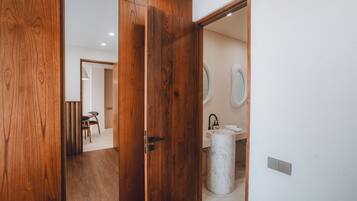 A wooden door leading to a bathroom with a sink and a mirror.