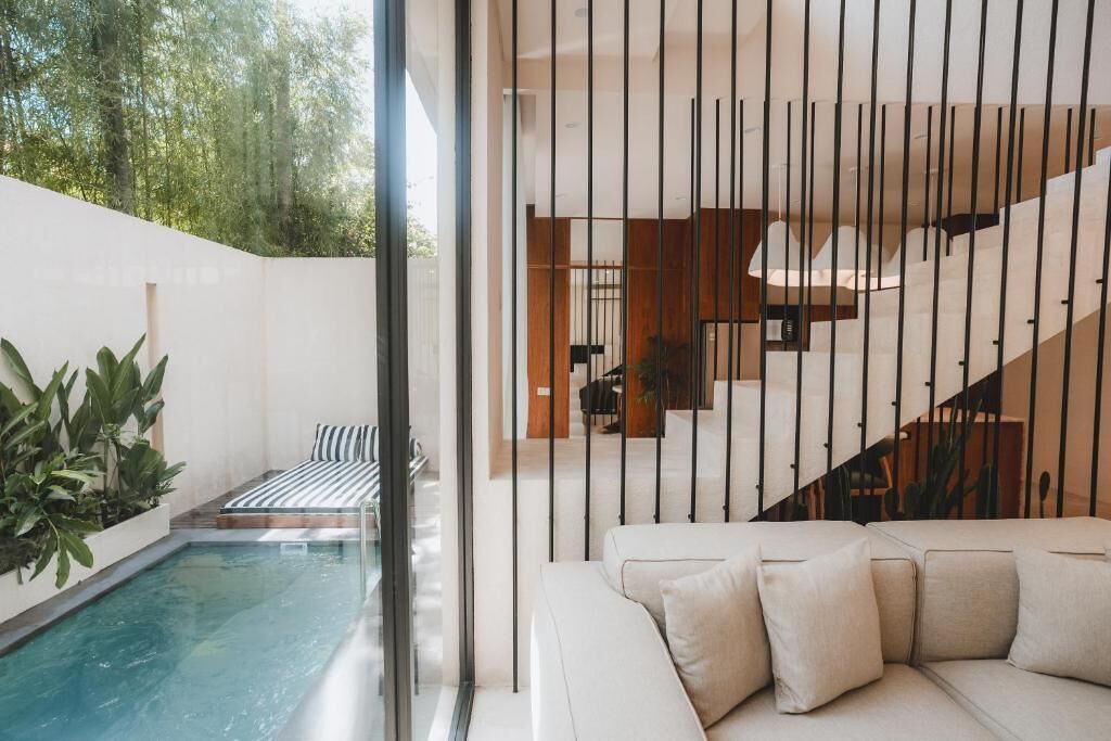 A modern interior with a pool, a sofa, and a staircase.