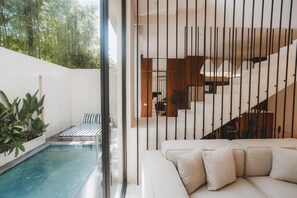 Un interior moderno con piscina, un sofá y una escalera.