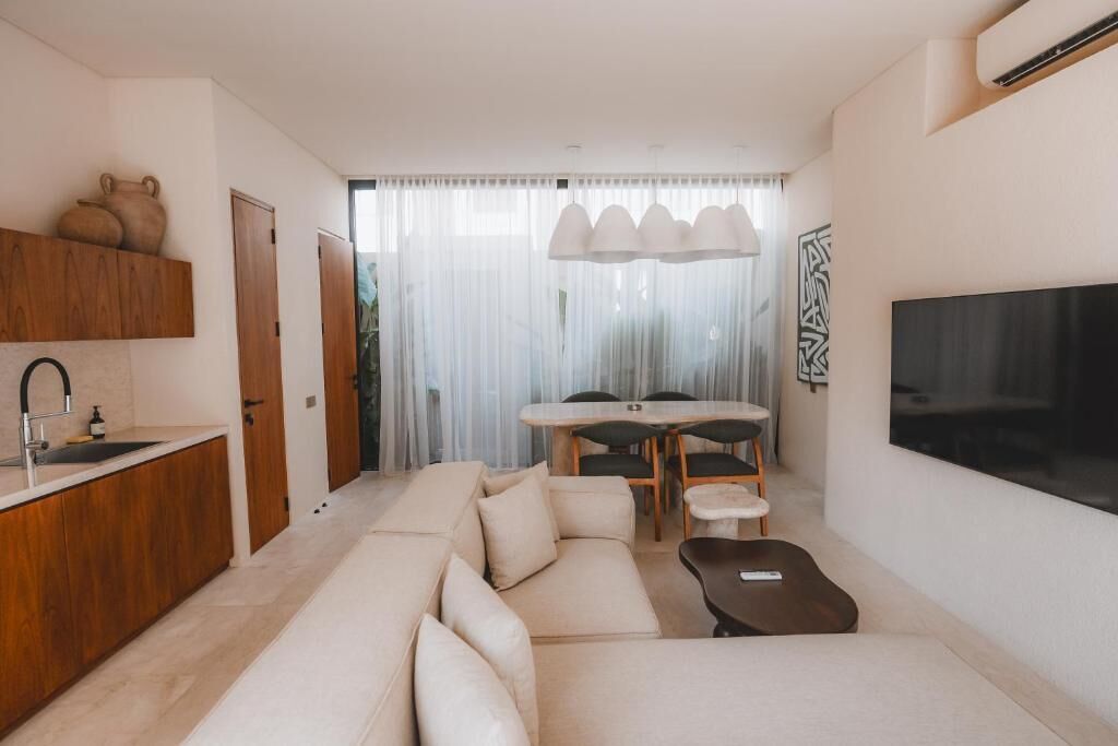 A modern living room with a sofa, a coffee table, a TV, and a dining area with a table and chairs.