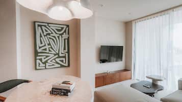 Una sala de estar moderna con una mesa redonda de mármol, un televisor montado y una gran obra de arte abstracto en la pared.