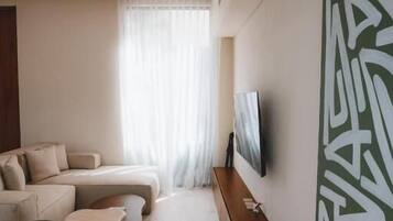 Un soggiorno moderno con un divano, un tavolino da caffè e una televisione a parete.