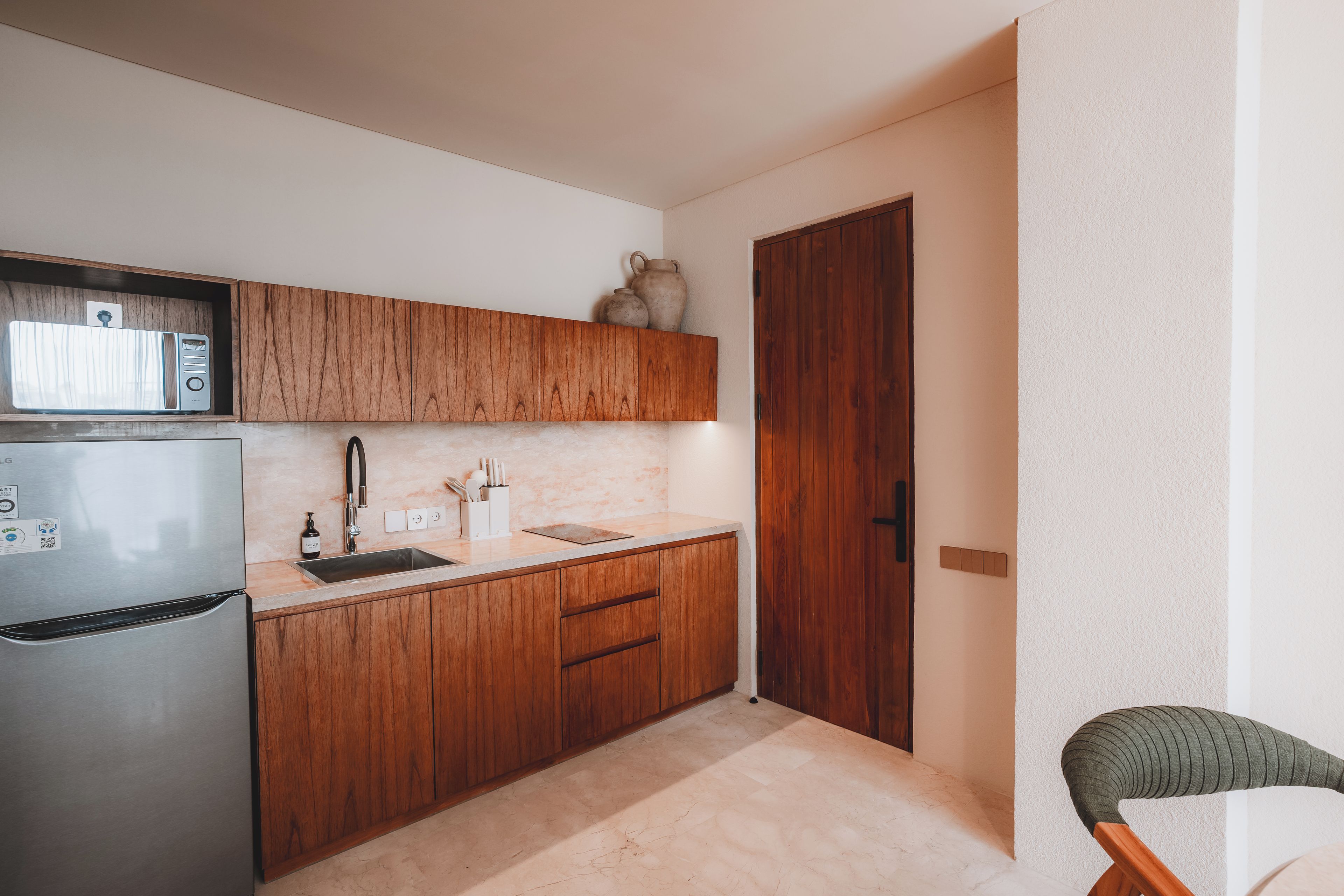 Eine kleine Küche mit Holzschränken, einem Edelstahlkühlschrank und einer Holztür.
