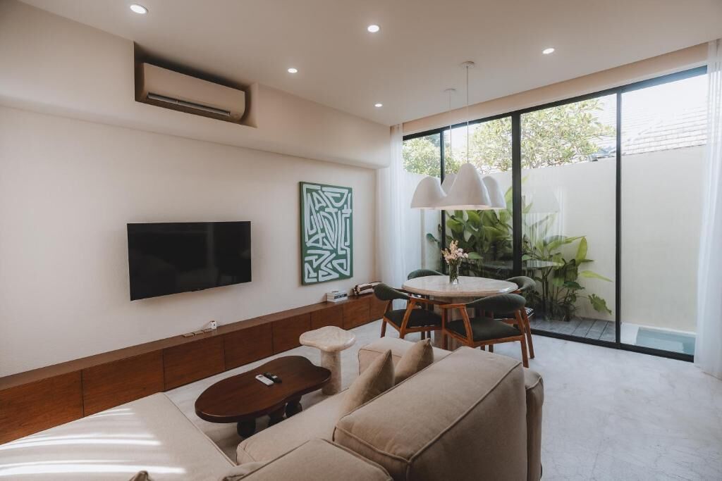 Una sala moderna con televisión de pantalla plana, una mesa de centro, un sofá y un comedor con mesa y sillas.