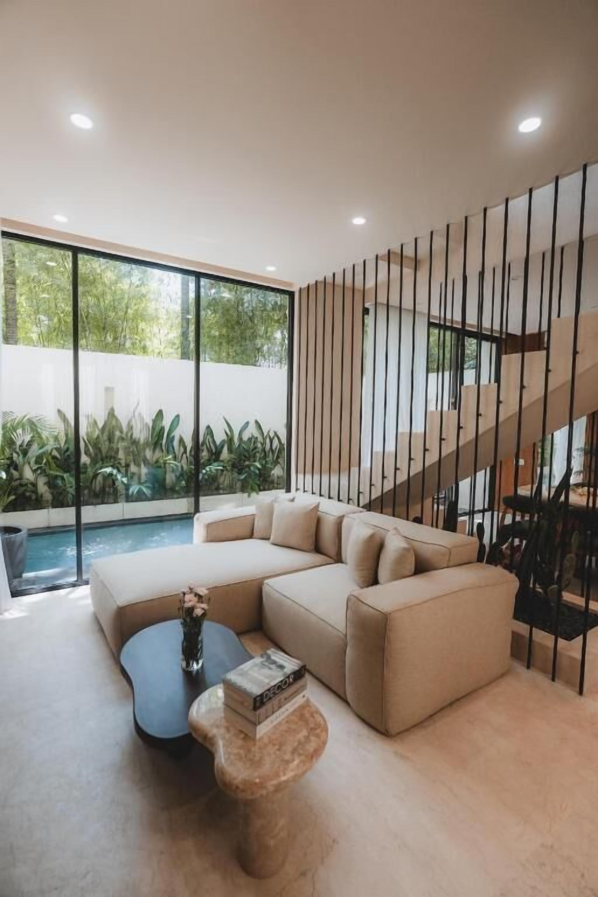A modern living room with a sectional sofa, a coffee table, and a staircase.