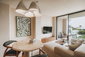 Una sala de estar moderna con una mesa redonda de mármol, un sofá y un televisor montado en la pared.