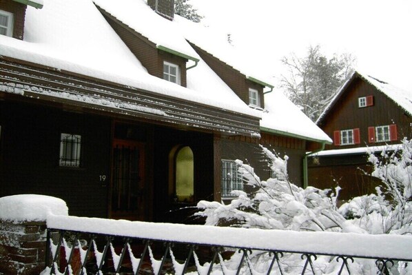 A wooden house with a snow-covered roof and a visible number '19' on the side.