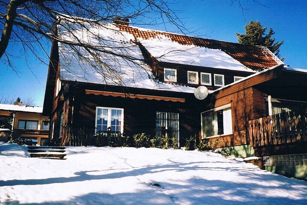 A two-story house with a snow-covered roof and a brick exterior.