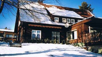 A two-story house with a snow-covered roof and a brick exterior.