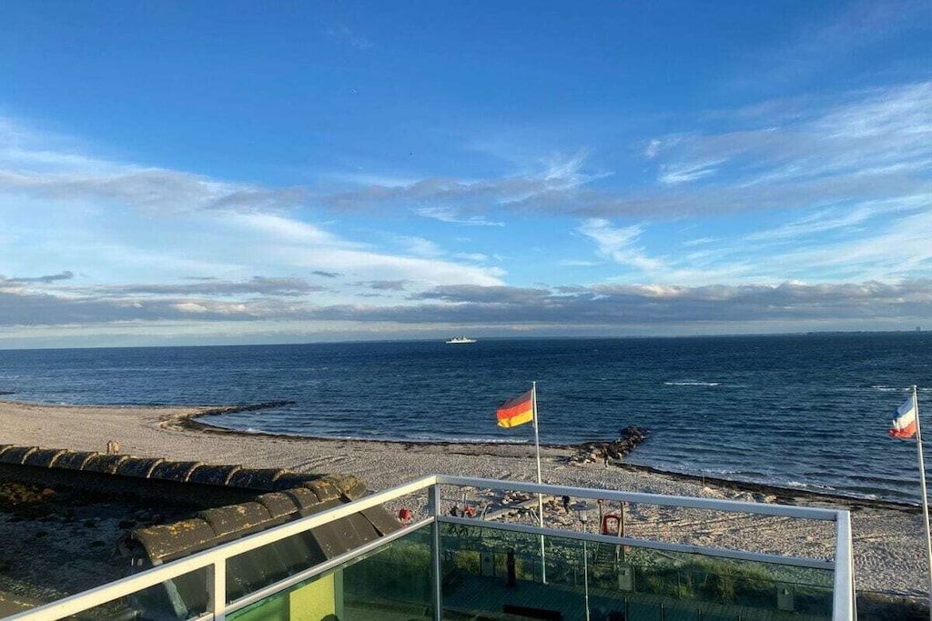 A beach with a clear sky, a flag, and a body of water.