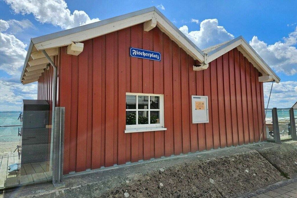 Ein rotes Gebäude mit einem Schild, auf dem 'Fischerdorf' steht, und einem Fenster.