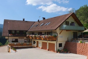 Ein zweistöckiges Gebäude mit geneigtem Dach, einem Balkon im oberen Geschoss und einem Schild, das ein Restaurant anzeigt.