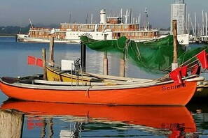Ein rotes Boot namens 'Schie' liegt in einer Marina festgemacht, mit anderen Booten und einem Gebäude im Hintergrund.