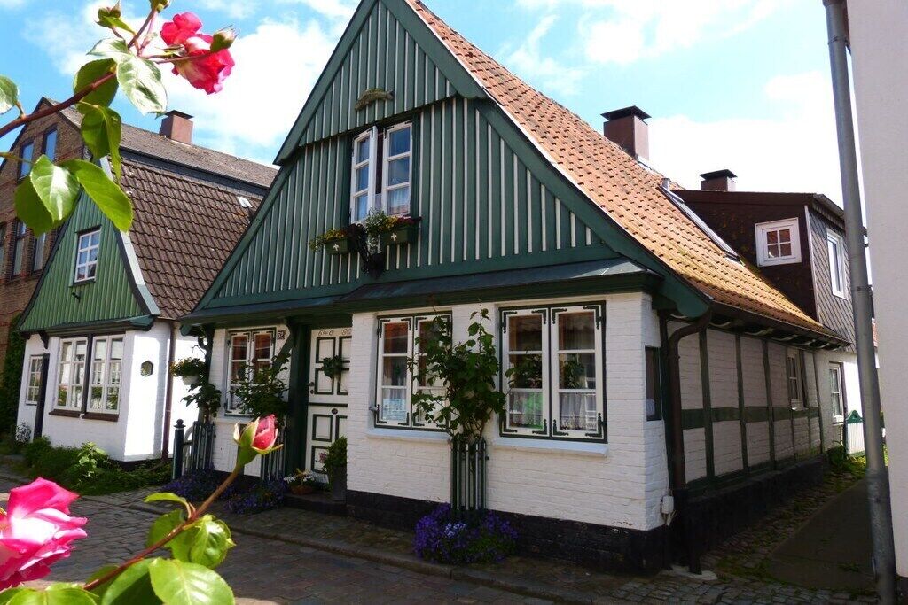 A traditional building with a steeply pitched roof, white walls with dark trim, and multiple windows.