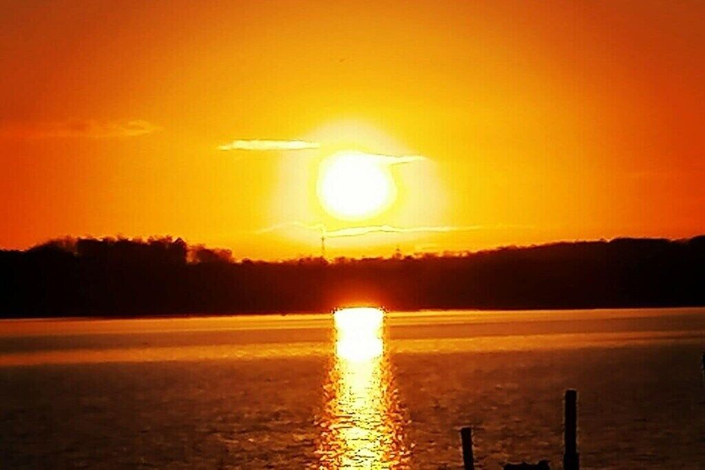 Ein Sonnenuntergang über einem Gewässer mit klarem Horizont.