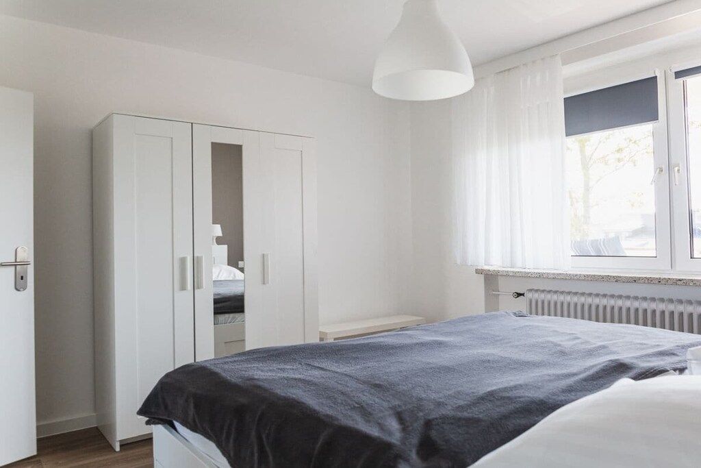 Ein Schlafzimmer mit einem Bett, einem Kleiderschrank und einem Fenster mit Vorhängen.