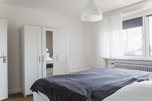 A bedroom with a bed, a wardrobe, and a window with curtains. - House Bärbel Apartment No. 5 (Cuxhaven)