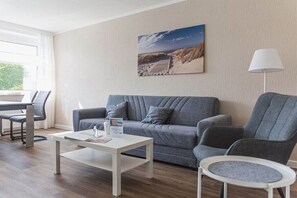 Un salon moderne avec un canapé gris, une table basse blanche et un fauteuil gris.