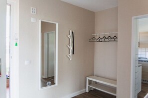 Une pièce avec un banc blanc, un porte-manteau et un miroir au mur.