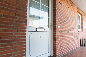 Un bâtiment en briques rouges avec une porte blanche portant le numéro 3.
