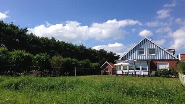 A two-story house with a large front porch, a separate garage, and a fenced yard. - Holiday home in Langeoog with swimming pool (Langeoog)