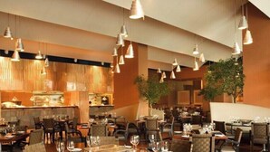 A restaurant with multiple dining tables and chairs, hanging pendant lights, and a bar area. - House Bärbel Apartment No. 4 (Cuxhaven)