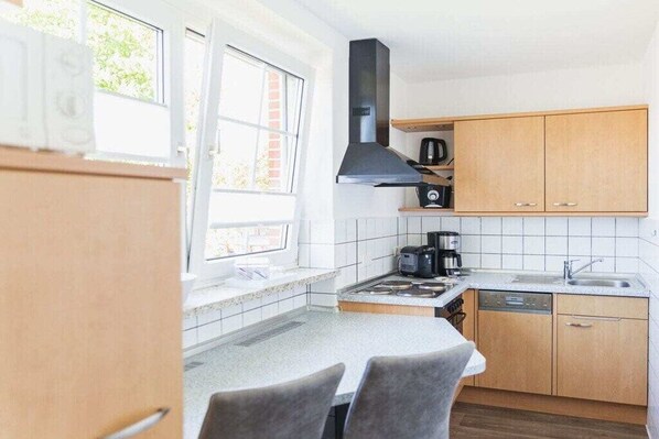 Une cuisine de taille réduite, dotée d’une fenêtre, d’une cuisinière, d’un évier et d’armoires en bois.