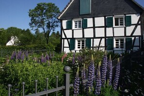 A traditional half-timbered house with a garden featuring purple flowers. - Holiday home with 3 bedrooms (Reichshof-Heischeid)