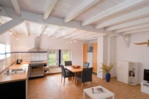 A modern kitchen with a dining area, wooden flooring, and a view of the outdoors. - Holiday home with 3 bedrooms (Reichshof-Heischeid)