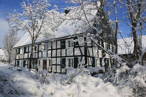 A traditional half-timbered building surrounded by snow-covered trees. - Holiday home with 3 bedrooms (Reichshof-Heischeid)