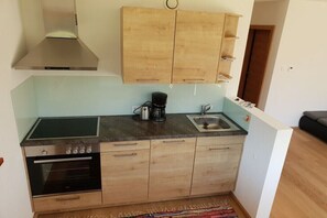 A compact kitchen with a stove, oven, coffee maker, and a sink. - Holiday apartment with 2 bedrooms (Aurach bei Kitzbühel)
