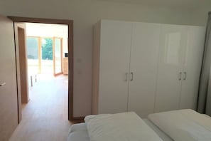A bedroom with a bed, a wardrobe, and an open door leading to a balcony. - Holiday apartment with 2 bedrooms (Aurach bei Kitzbühel)