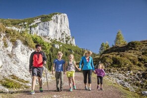 Un groupe de personnes fait de la randonnée sur un sentier, avec une falaise rocheuse en arrière-plan.
