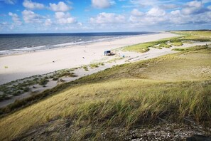 Une plage avec des dunes, un poste de surveillance des sauveteurs et un ciel dégagé.