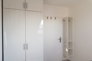 A room with a wardrobe, a door with a handle, and a wall-mounted shelf. - Holiday apartment with 1 bedroom (Wangerland)
