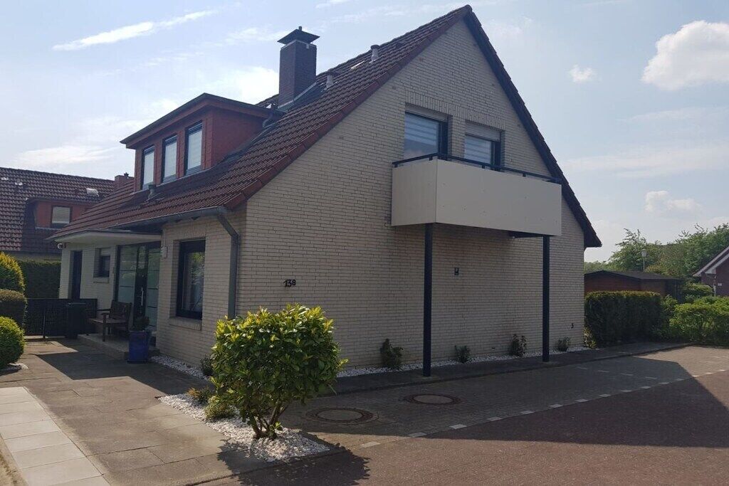 Une maison d’habitation à deux étages, dotée d’un toit en pente, d’une cheminée bien visible et d’un petit jardin devant, agrémenté d’un arbuste.