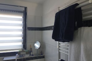 A bathroom with a window, a towel rack, a mirror, and toiletries. - Holiday apartment with 1 bedroom (Wangerland)
