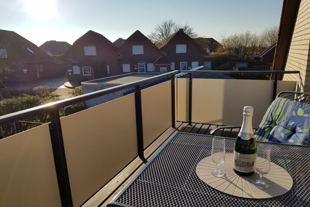 A balcony with a table, a bottle of champagne, and two glasses.
