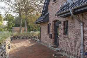 A brick building with a stone retaining wall and a paved walkway. - Holiday home in St. Peter-Ording with sauna (St.Peter-Ording)