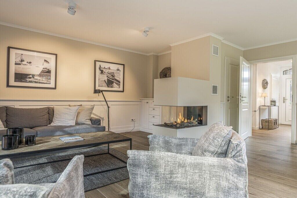 A living room with a sofa, armchairs, a coffee table, a fireplace, and framed pictures on the wall.