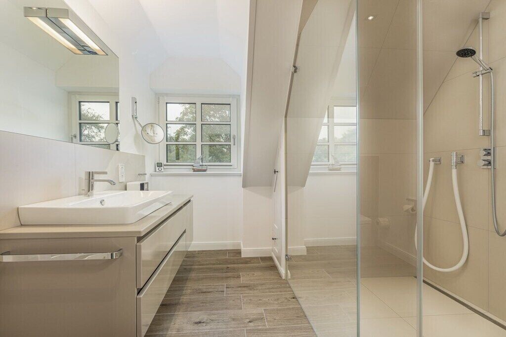 Une salle de bain moderne avec une douche à parois de verre, un lavabo et un miroir.