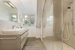 A modern bathroom with a glass shower enclosure, a sink, and a mirror. - Holiday home in St. Peter-Ording with sauna (St.Peter-Ording)