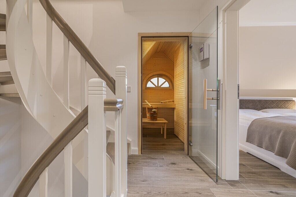Een slaapkamer met een bed, een houten hoofdeinde en een glazen deur naar een badkamer.