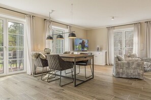A spacious living area with a dining table, chairs, a television, and a sofa. - Holiday home in St. Peter-Ording with sauna (St.Peter-Ording)